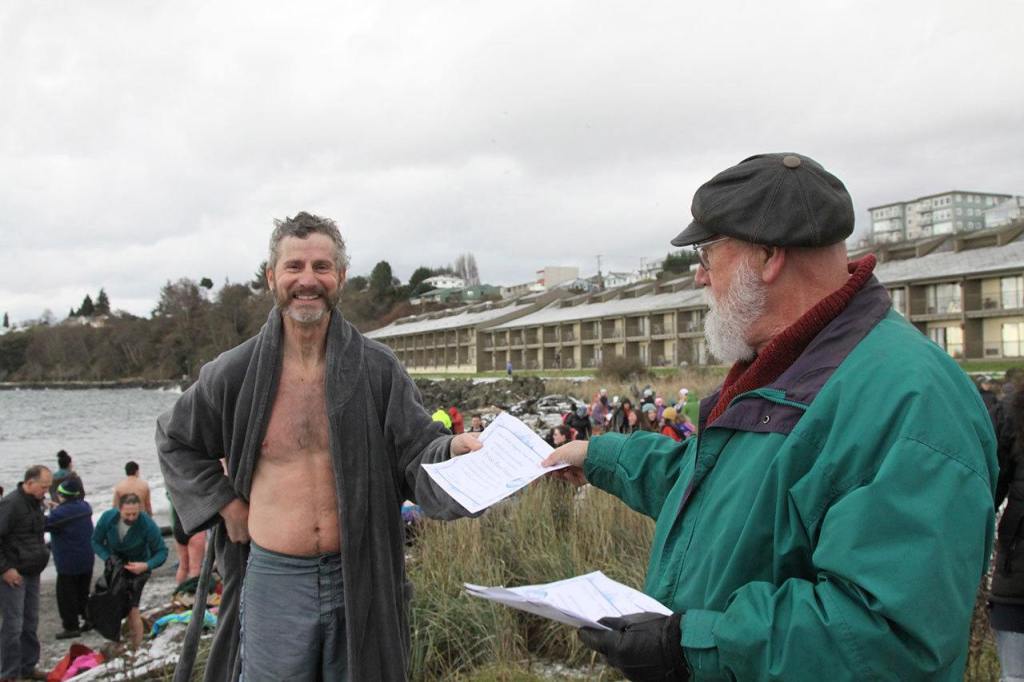 Drew McGinley of Port Angeles receives his polar bear plunge certificate from Rick Oden on Sunday morning. Sunday was McGinley&rsquo;s 29th consecutive dip. (Dave Logan/for Peninsula Daily News)