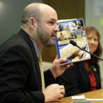 Mike Hiestand, a staff attorney with the Student Press Law Center, holds a copy of his book, Law of the Student Press, as he speaks during a Senate hearing at the Capitol on Thursday in Olympia. (Ted S. Warren/The Associated Press)