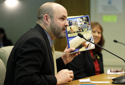 Mike Hiestand, a staff attorney with the Student Press Law Center, holds a copy of his book, Law of the Student Press, as he speaks during a Senate hearing at the Capitol on Thursday in Olympia. (Ted S. Warren/The Associated Press)