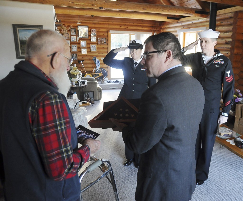As Pearl Harbor veteran Bob Rains talks with Tim Katona, president of the Navy League Bremerton-Olympic Peninsula Council, YN2 (yeoman) Kate Pope and YN1 (yeoman) Hogan Sternbeck stand in salute. Rains accepted a flag from Katona that was flown over the USS Arizona memorial in Hawaii. (Michael Dashiell/Olympic Peninsula News Group)
