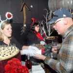 Rod Lee of Sequim, right, receives a chocolate confection from Harbinger Winery employee Amber Witherow, left, as volunteer Suzie Bennett waits in the background to serve chocolate during last weekend&rsquo;s Wine, Cider & Chocolate Tour at the Port Angeles winery. (Keith Thorpe/Peninsula Daily News)