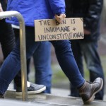 A person walks away from the federal courthouse in Seattle carrying a sign that reads &ldquo;The Ban is Inhumane and Unconstitutional&rdquo; on Friday following a hearing in federal court in Seattle. (Ted S. Warren/The Associated Press)