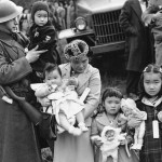 In this March 30, 1942, photo, Cpl. George Bushy, left, a member of the military guard that supervised the departure of 237 Japanese people for California, holds the youngest child of Shigeho Kitamoto, center, as she and her children are evacuated from Bainbridge Island. Roughly 120,000 Japanese immigrants and Japanese-Americans were sent to desolate camps that dotted the West because the government claimed they might plot against the U.S. (The Associated Press)