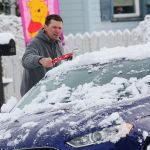 Chris Spence brushes snow off his mother&rsquo;s car on Monday. (Jesse Major/Peninsula Daily News)