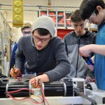 Sequim High School Robotics student Liam Byrne, foreground, works on a component of the robotic chassis, assisted by volunteer mentor Jerry Bileck, Brenton Barnes, Riley Scott and Riley Chase, from left. (Patsene Dashiell)