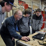 Volunteer mentor Martin Cahoon, center, shares a schematic on the laptop in the school shop with Robotics students Max Koonz, Nick Charters and Josh King, from left. (Patsene Dashiell)