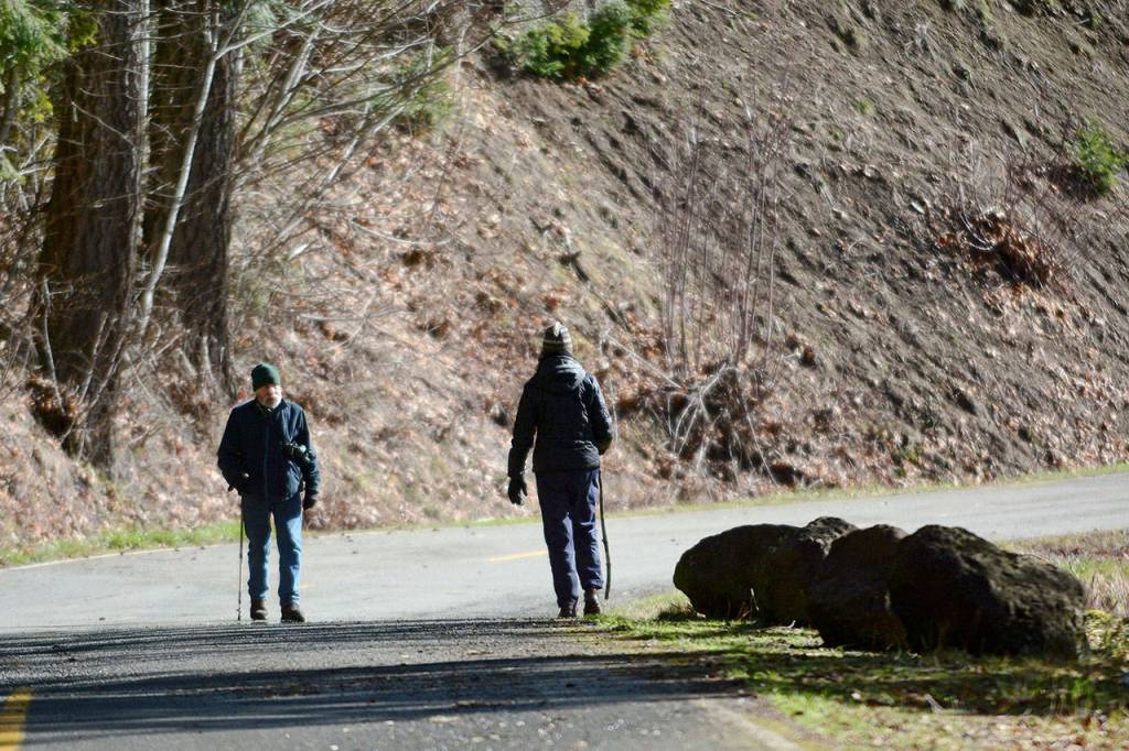 Two people walk on Olympic Hot Springs Road in Olympic National Park last Thursday. The road is closed to vehicle traffic. (Jesse Major/Peninsula Daily News)