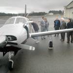 Chris Dupin, chief financial officer for Zephyr Air, center left, talks with North Olympic Peninsula business leaders next to a Piper PA-46 Malibu aircraft belonging to the airline during a promotional visit to William R. Fairchild International Airport in Port Angeles in February. (Keith Thorpe/Peninsula Daily News)