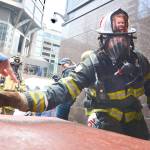 Port Angeles Fire Department firefighter Dan Montana waves his wristband timing chip over a timing mat as he starts his climb up the tower. Picture on his helmet is of Jocelin Hough of Sequim, who is battling acute lymphocytic leukemia. (Jay Cline)