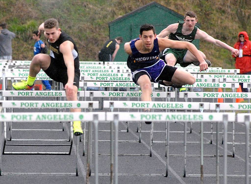 Keith Thorpe/Peninsula Daily News Riley Martin of Sequim, center, moves into first place ahead of Nathanael Kjormoe of North Kitsap, left, to win the boys 110m hurdles during Fridays Port Angeles Invitational at Port Angeles High School. Port Angeles&rsquo; Daimon Batchelor, right, took forth in the event.