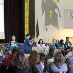 Patty Brandt auctions items over the speakers at the Forks High School commons and also over Forks Broadcasting 96.7 while FHS seniors dressed show items to be auctioned, take bids from callers and from those who gathered for the 53rd annual Quillayute Valley Scholarship Auction, and enter the bidding on the overhead projectors. (Lonnie Archibald/for Peninsula Daily News)