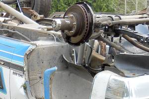 Two escape injury when truck loses wheel, strikes tree and overturns