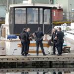 Port Angeles police investigators confer with Clallam County coroner Mark Nichols, second from left, after the body of a man was found floating in the water at Port Angeles Boat Haven on Wednesday morning. (Keith Thorpe/Peninsula Daily News)