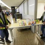 Port of Seattle workers Aaron Washington, left, and Tracy Jenkins carry a table and snacks into a room near where passengers arrive on international flights at Seattle-Tacoma International Airport on Tuesday. (Ted S. Warren/The Associated Press)