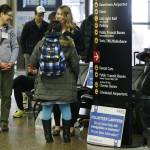 Asti Gallina, right, and Emily McDaniel, left, both volunteer law students, talk to a traveler as they staff a station near where passengers arrive on international flights at Seattle-Tacoma International Airport on Tuesday. (Ted S. Warren/The Associated Press)