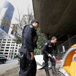 In this photo taken March 23, Seattle Police Officers Wes Phillips, left, and Tori Newborn talk with Corvin Dobschutz as part of a new team of outreach workers and officers that go out and connect homeless people to services, as the homeless man sits in his tent below a freeway and next to downtown Seattle. (Elaine Thompson/The Associated Press)
