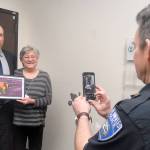 Port Angeles Police Chief Brian Smith, right, takes a photograph of Edward Bluhm, an investigator with U.S. Homeland Security, left, and Becca Korby, executive director of Healthy Families of Clallam County, after Bluhm was presented with an award of appreciation by Korby during Tuesday&rsquo;s Clallam County commissioners meeting in Port Angeles. (Keith Thorpe/Peninsula Daily News)