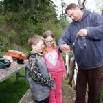 Steve Mullensky/for Peninsula Daily News                                Port Orchard&rsquo;s Jim Dunn show off his trout catch to son, Joshua, 8, and daughter Alia, 10, while fishing on the opening day of lowland lake fishing at Anderson Lake on Saturday.