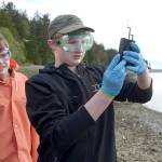 Blue Heron eighth-graders Andru Goodlin, left, and Odin Smith study water samples they collected from the south side of Indian Island. (Cydney McFarland/Peninsula Daily News)