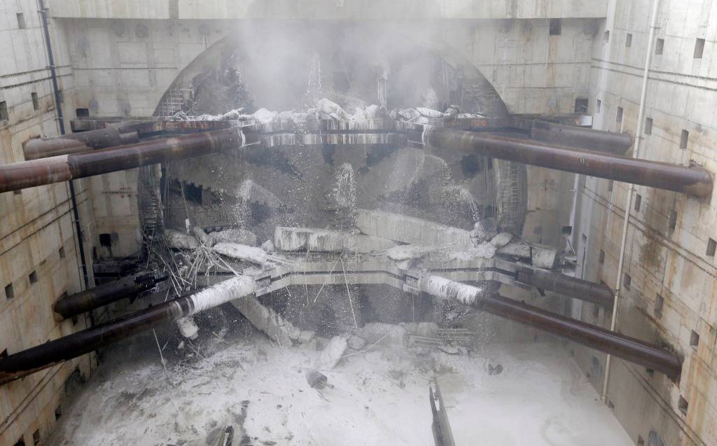 A massive tunneling machine breaks through a 5-foot concrete wall as it completes boring for the state Highway 99 route Tuesday under Seattle. (Elaine Thompson/The Associated Press)