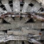 A pair of workers climbs out between cutting blades near the top of a massive tunneling machine Tuesday under Seattle. (Elaine Thompson/The Associated Press)