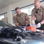 Clallam County Sheriff&rsquo;s Deputies Eric Morris and Paul Federline sift through guns, money, cellphones, methamphetamine and heroin Sunday discovered after someone was reported driving recklessly on U.S. Highway 101 in Port Angeles. (Jesse Major/Peninsula Daily News)