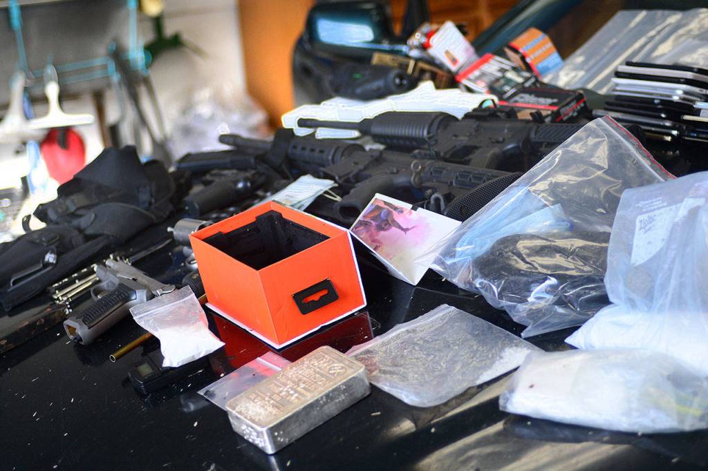 Guns, money, cellphones, heroin and methamphetamine sit on the hood of the car Clallam County Sheriff&rsquo;s deputies searched Sunday. (Jesse Major/Peninsula Daily News)