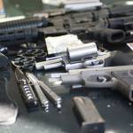 Two handguns, two rifles, brass knuckles, two knives and a fake gun sit on the hood of a car Clallam County Sheriff&rsquo;s deputies searched Sunday. (Jesse Major/Peninsula Daily News)