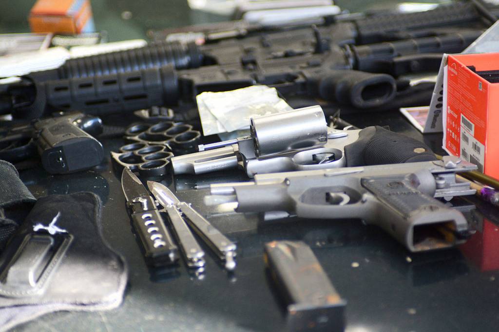 Two handguns, two rifles, brass knuckles, two knives and a fake gun sit on the hood of a car Clallam County Sheriff&rsquo;s deputies searched Sunday. (Jesse Major/Peninsula Daily News)
