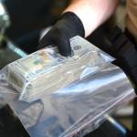 A Clallam County Sheriff&rsquo;s deputy holds a wad of cash, made up mostly of $20s, discovered during a vehicle search Sunday. (Jesse Major/Peninsula Daily News)