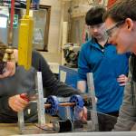 Sequim High School robotics students, from left, Nick Charters, Riley Chase and Josh King, survey a robotic component before a competition in early March. The team qualified for the FIRST Robotics Competition world championship in Houston and will take their robot there to compete against teams from across the globe. (Patsene Dashiell/Sequim School District)