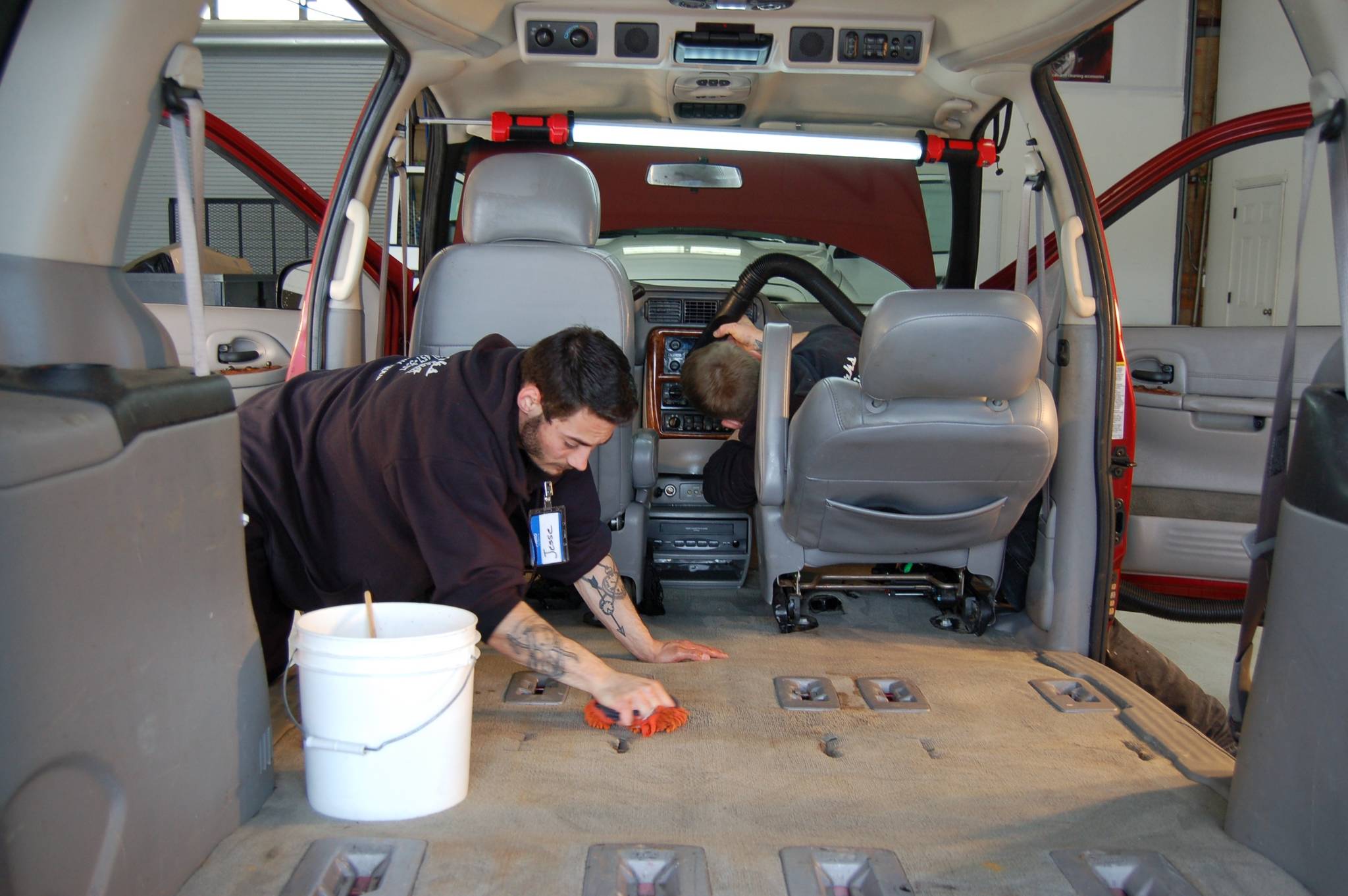 Employees of Skunkworks Auto Detailing & Body Repair Jesse Bailey, left, and Chris Babcock, right, volunteer to detail a donated van that will go toward Olympic Community Actions Programs&rsquo; senior nutrition program. (Erin Hawkins/Olympic Peninsula News Group)