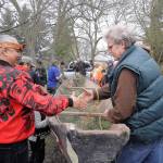 Vince Penn of the Quileute Tribe, left, and Frank Hanson, education and outreach coordinator at the University of Washington&rsquo;s Olympic Natural Resources Center, shake hands as a handmade canoe carved by William E. Penn is removed from Pioneer Memorial Park on April 8. (Michael Dashiell/Olympic Peninsula News Group)