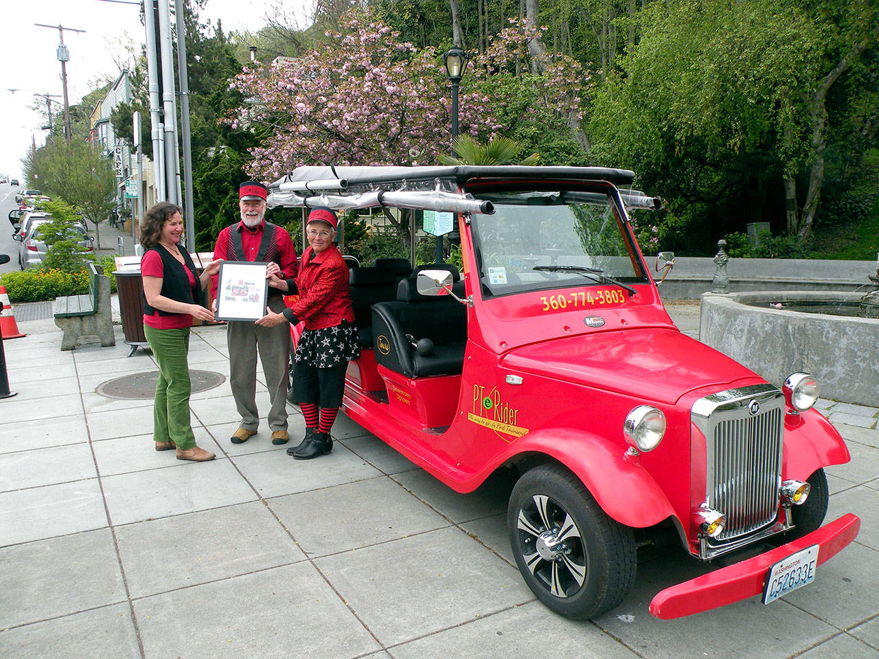 Port Townsend Main Street board member Connie Segal, left, delivers the &ldquo;Sustainable Future&rdquo; award to Myron Gauger and Kate Dwyer, owners of PT eRider. (Mari Mullen)