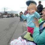 Nine-month-old Aivery Stuhr waves in delight while watching her very first parade with mother Rebecca White of Sequim. (Keith Thorpe/Peninsula Daily News)