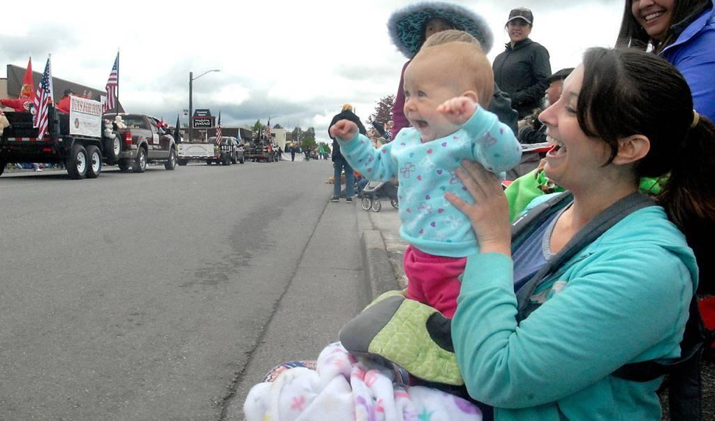 Nine-month-old Aivery Stuhr waves in delight while watching her very first parade with mother Rebecca White of Sequim. (Keith Thorpe/Peninsula Daily News)