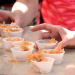 Patrons of Saturday&rsquo;s farmers market dig into samples of seared salmon with spicy cabbage, prepared by Arran Stark as one of three chef demonstrations at this weekend&rsquo;s Artisan Food Festival. (Cydney McFarland/Peninsula Daily News)