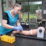 Student medical assistant Christina Wommack of Port Angeles practices her phlebotomy skills on an artificial arm Thursday in a clinical lab seminar classroom in the newly constructed Allied Health & Early Childhood Education Building on the Port Angeles campus of Peninsula College. (Keith Thorpe/Peninsula Daily News)