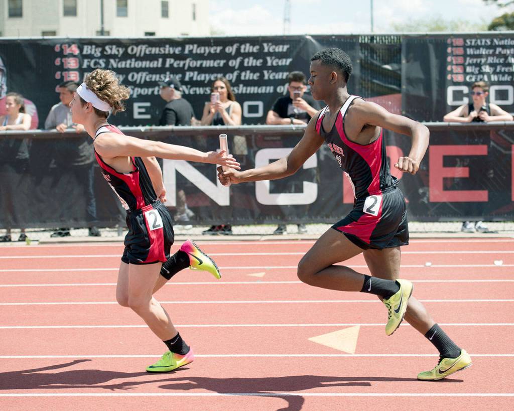 Casey Bruner/for Peninsula Daily News Neah Bay&rsquo;s Anthony Bitegeko hands the baton to Logan Halttunen in the preliminaries of the 4x100 relay at the State 1B Track and Field Championships in Cheney on Friday.