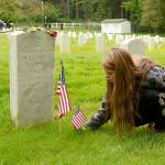 Oracle Holms of Port Hadlock places flags at the gravestones of veterans in the cemetery at Fort Worden on Monday. (Cydney McFarland/Peninsula Daily News)