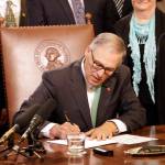 Gov. Jay Inslee signs a bill Tuesday in Olympia that seeks to bring Washington state into compliance with the federal REAL ID Act. (Rachel La Corte/The Associated Press)