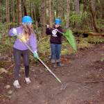 Sequim High freshmen Kjirstin Foresman, left, and Mazie Whitteker, use rakes to clear debris from a new trail they and other high-schoolers worked to build on the Miller Peninsula last week. They learned about sharing the trail with bicyclists and stock, careers in forestry management and different tools for clearing trails. (Matthew Nash/Olympic Peninsula News Group)