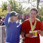 North Olympic Discovery Marathon winner Ryan Cox of Bainbridge Island is welcomed by Port Angeles City Councilwoman Cherie Kidd at the finish line. (Dave Logan/for Peninsula Daily News)