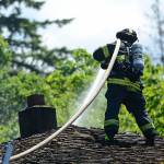 Port Angeles firefighter Mark Karjalainen sprays down the roof of a Port Angeles home that caught fire Sunday afternoon. (Jesse Major/Peninsula Daily News)