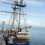 A passerby leans over the railings at the Northwest Maritime Center dock to check out the Hawaiian Chieftain, one of a dozen tall ships scheduled to sail through Admiralty Inlet today. (Cydney McFarland/Peninsula Daily News)