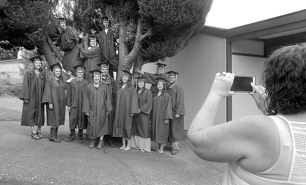 Crescent School secretary Linda Sage, right, takes a group photo of members of the school&rsquo;s class of 2017 before the seniors prepared to march to commencement in the gym Saturday in Joyce. Fifteen seniors were eligible for graduation for the 2016-17 academic year.