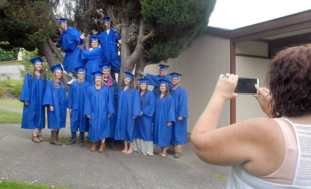 Crescent School secretary Linda Sage, right, takes a group photo of members of the school&rsquo;s class of 2017 before the seniors prepared to march to commencement in the gym Saturday in Joyce. Fifteen seniors were eligible for graduation for the 2016-17 academic year. (Keith Thorpe/Peninsula Daily News)