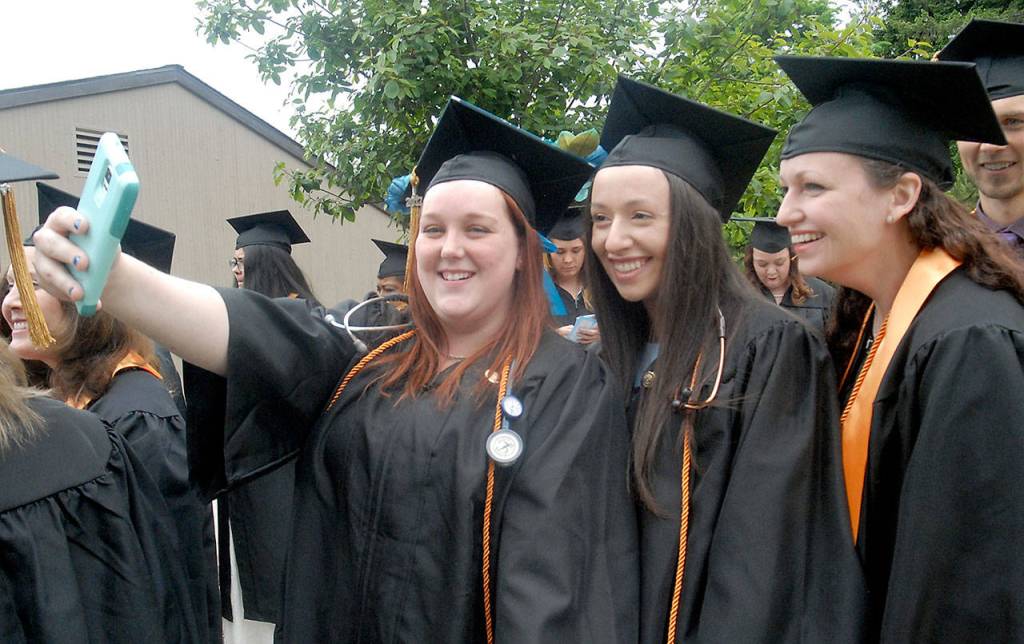 Nursing students, from left, Carrie Bertman of Port Angeles, Michelle Abell-Sietz of Sequim and Jessica Meek of Port Angeles pose for a group selfie while lining up for commencement ceremonies Saturday on the Port Angeles campus of Peninsula College. A total of 275 students were set to take part in the proceedings out of 486 students receiving 600 degrees and certificates. (Keith Thorpe/Peninsula Daily News)