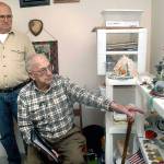 Tom McKeown Jr., left, looks on as his father, Tom McKeown Sr., points out memoribilia from his military service in World War II. The Port Angeles men, both of whom served in the U.S. Marine Corps, will ride aboard a vintage B-17 bomber aircraft during a visit by the Wings of Freedom on Wednesday at William R. Fairchild International Airport in Port Angeles. (Keith Thorpe/Peninsula Daily News)