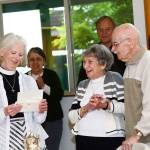 The Rev. Gail Wheatley of St. Andrews Episcopal Church, left, reads a letter from Gov. Jay Inslee congratulating Elaine and Ed Berrington, center and right, on their 75th anniversary. (Jesse Major/ Peninsula Daily News)